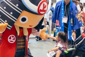 写真：マスコットの着ぐるみにハイタッチする子供